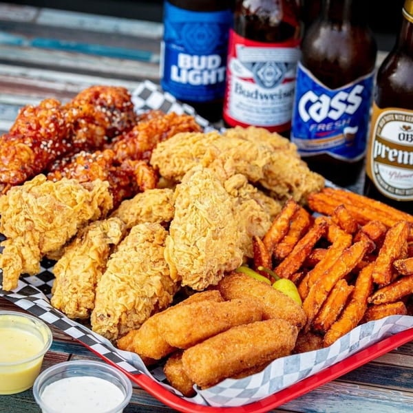 Legend Hot Chicken platter with fried chicken, sweet potato fries, mozzarella sticks, and beer bottles.