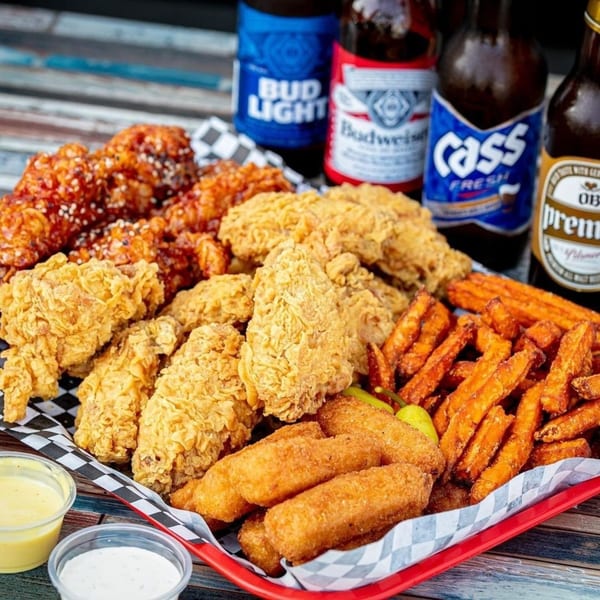Legend Hot Chicken platter with fried chicken, sweet potato fries, mozzarella sticks, and beer bottles.