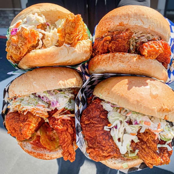 Four Legend Hot Chicken sandwiches, piled high with crispy chicken, coleslaw, and pickles.